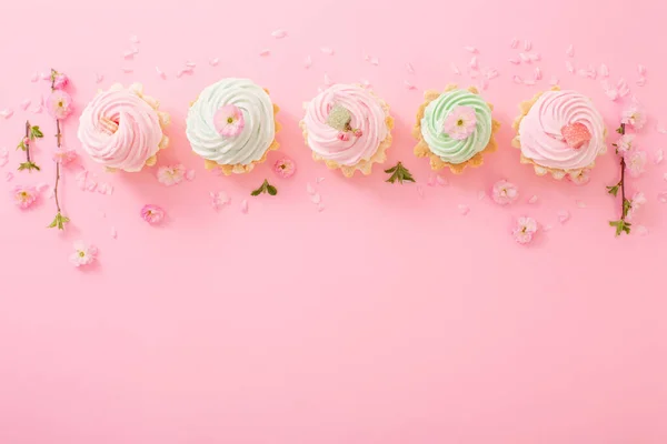 ピンクと緑のカップケーキピンクの背景に春の花 — ストック写真