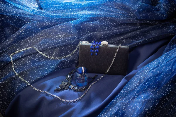 Parfüm Şişesi Siyah Debriyaj Mavi Gece Elbisesinin Arka Planında Mücevherler — Stok fotoğraf