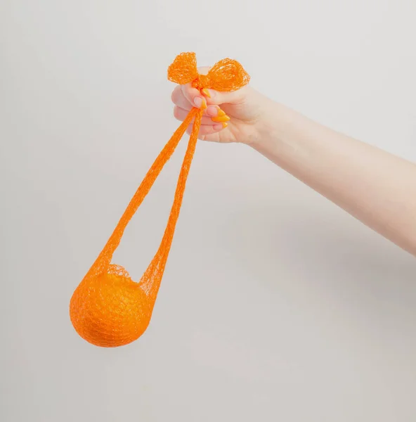オレンジと合成のストリングバッグを持つ女性の手 — ストック写真