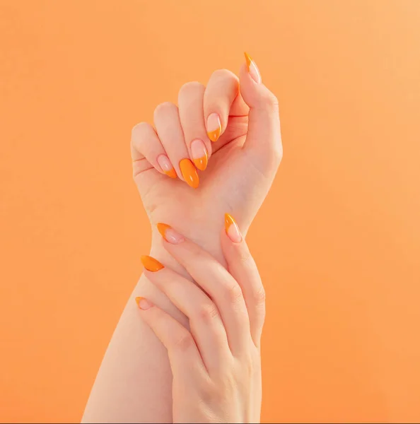 Kvinnlig Hand Med Manikyr Orange Bakgrund — Stockfoto