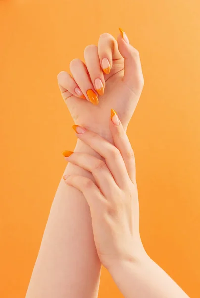 オレンジ色の背景にマニキュアを持つ女性の手 — ストック写真