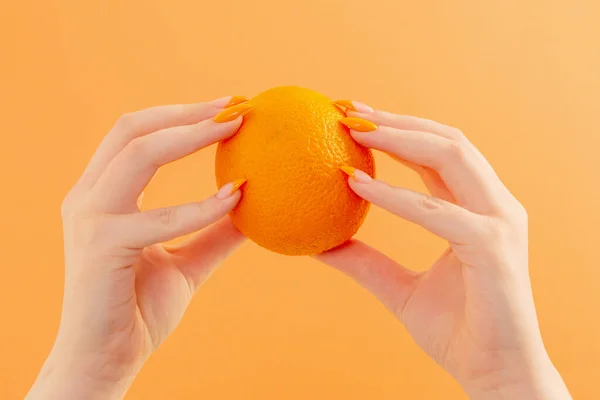 female hand with orange on orange background