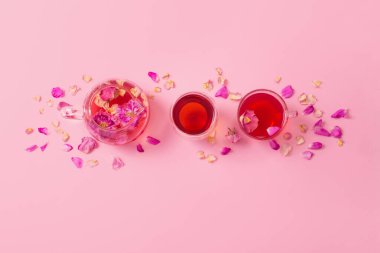 Pembe arka planda cam çaydanlıkta gül yapraklı çay