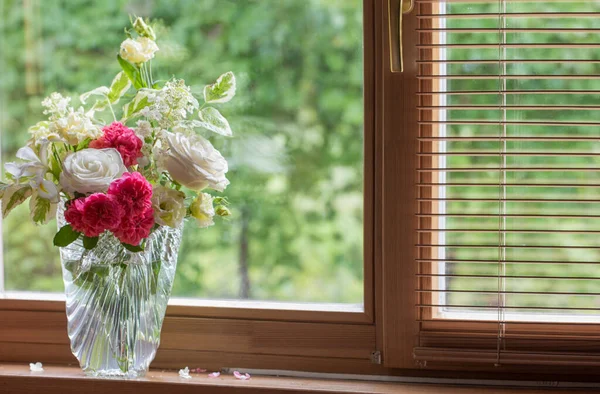 summer bouquet in glass vase  on windowsill in wooden house