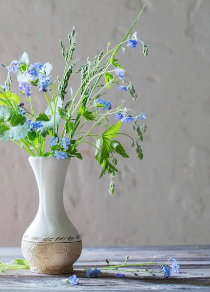 wild flowers  in vase  on background white old wall