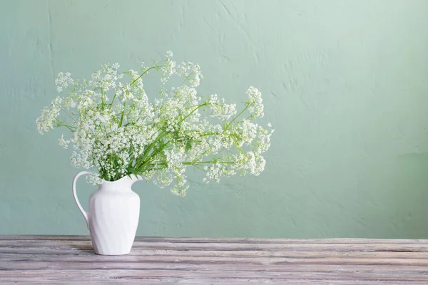 stock image white wild flowers in jug on background green wall