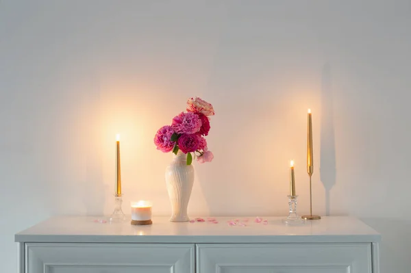 Vazodaki Pembe Güller Arkadaki Beyaz Duvarda Yanan Mum — Stok fotoğraf
