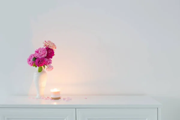 Vazodaki Pembe Güller Arkadaki Beyaz Duvarda Yanan Mum — Stok fotoğraf