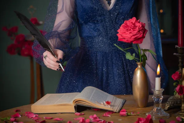 穿着蓝色复古服装的年轻漂亮的女人 带着书在黑暗的房间里放在桌子上 — 图库照片