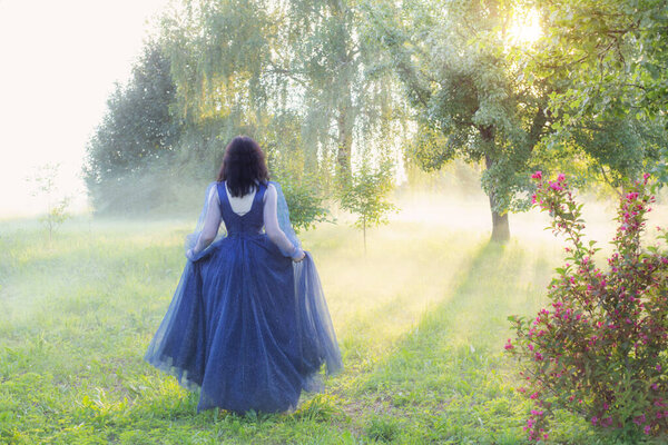 Young beautiful woman in blue vintage dress in magic forest