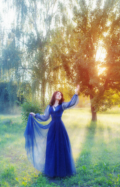 Young beautiful woman in blue vintage dress in magic forest