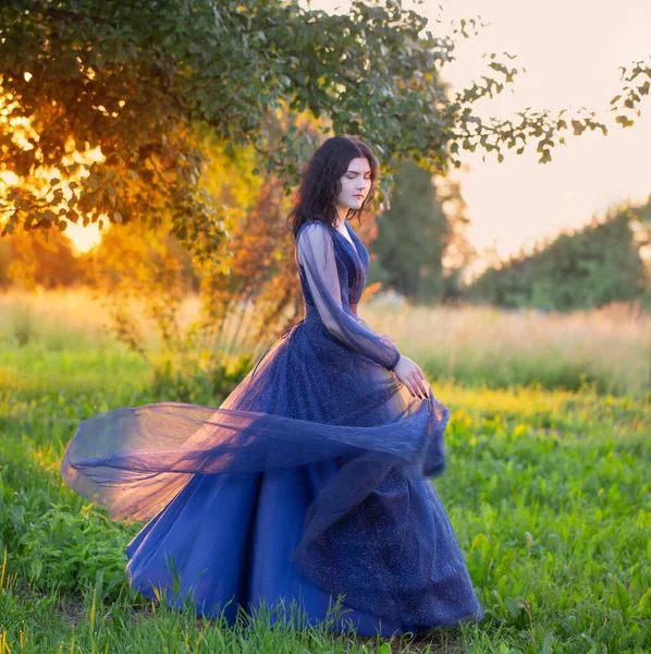 年轻美丽的女人 穿着蓝色的老式衣服 日落时开着白花 — 图库照片
