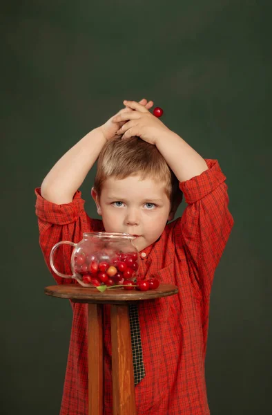 Liten Rolig Pojke Med Körsbär Bakgrunden Mörkgrön Vägg — Stockfoto