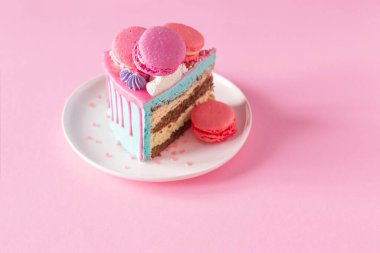 Pembe ve mavi desenli bir parça kek beyaz tabakta pembe arka planda