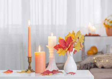 Evdeki beyaz masada sonbahar dekoru ile mum yakmak.