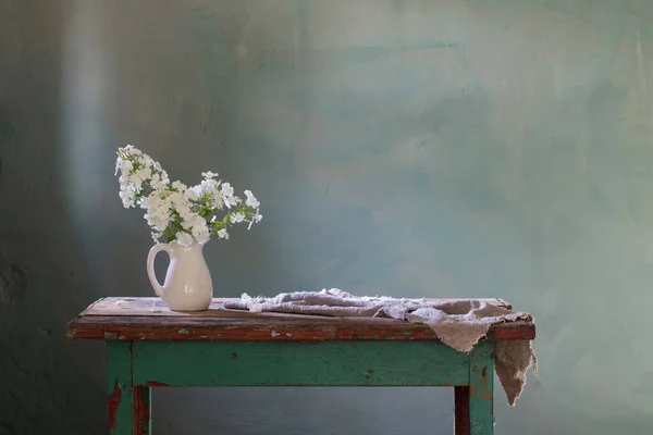 緑の背景に古い木のテーブルの上の花瓶のPhloxes — ストック写真