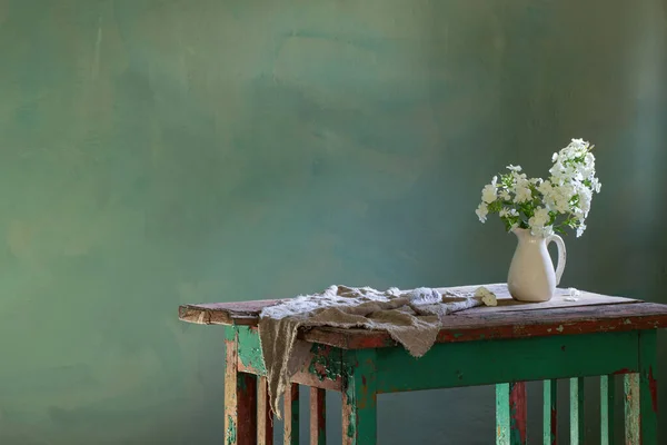 緑の背景に古い木のテーブルの上の花瓶のPhloxes — ストック写真