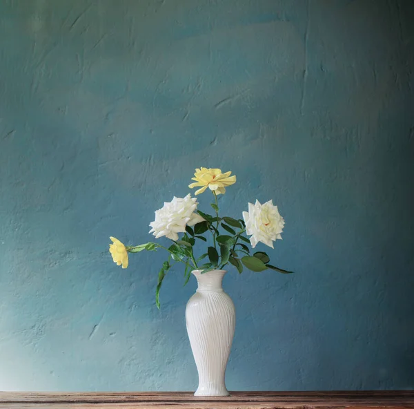 背景の木のテーブルの上の白い花瓶のバラ暗い壁 — ストック写真