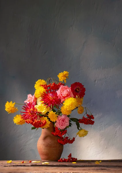 red and yellow flowers on jug in sunlight on background dark wall