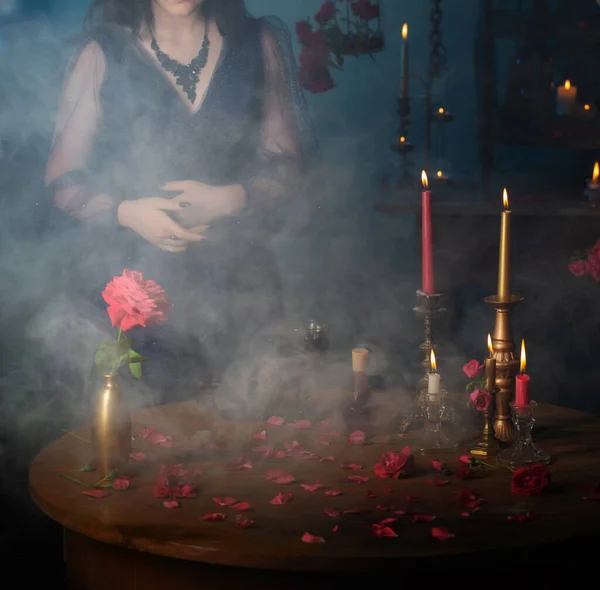 年轻美丽的女人穿着蓝色的老式衣服 红玫瑰和神奇的药水在黑暗的房间里 — 图库照片