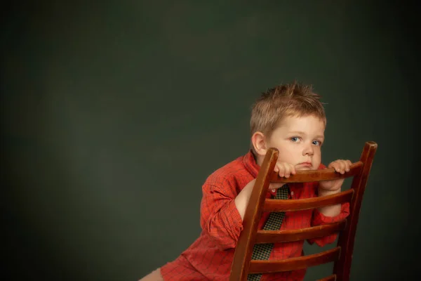 Menino Triste Camisa Vermelha Cadeira Velha Fundo Verde Escuro — Fotografia de Stock