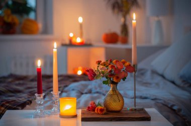 Vazoda sonbahar kasımpatısı ve yatak odasında yanan mumlar.