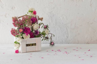 Beyaz arka planda ahşap sepette pembe ve beyaz çiçekler