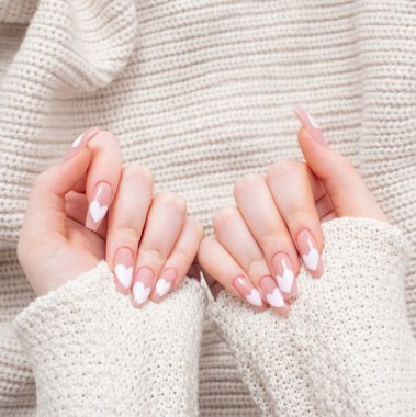 Güzel, uzun tırnaklı, manikürlü, kışın giydiği kalp desenli kadın elleri.