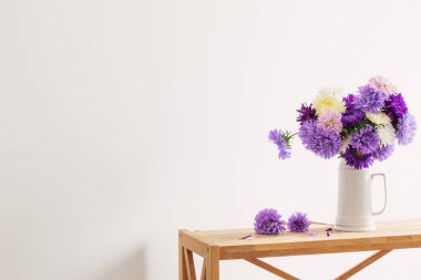 Beyaz sürahide beyaz sürahi içinde güzel bir buket aster.