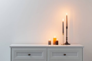 Beyaz iç kısımda, beyaz ahşap rafta mum yakmak.