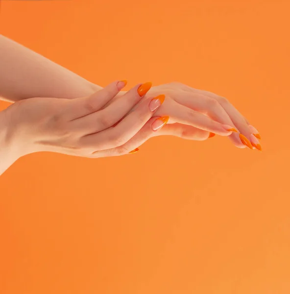 Kvinnlig Hand Med Manikyr Orange Bakgrund — Stockfoto