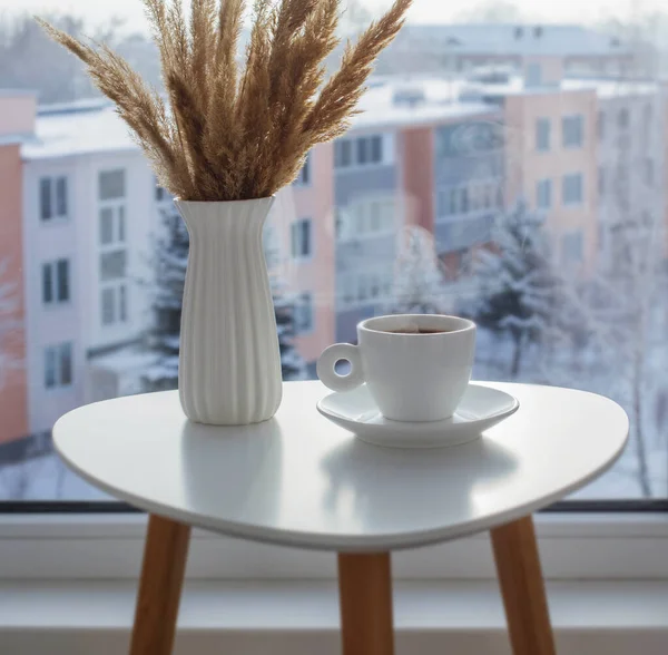 冬には窓辺の白いテーブルにコーヒーを飲み — ストック写真