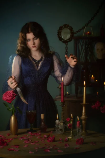 年轻美丽的女人穿着蓝色的老式衣服 带着匕首在黑暗的房间里 — 图库照片