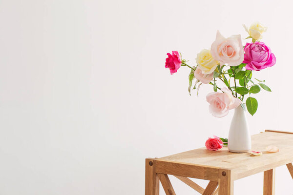 pink and white roses in white ceramic vase on white background
