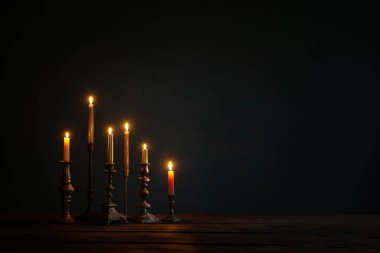 Koyu arkaplanda eski şamdanlarla mum yakmak