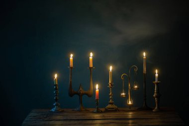 Koyu arkaplanda eski şamdanlarla mum yakmak