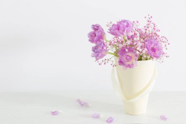 Beyaz masada pembe laleler ve çigila demeti.