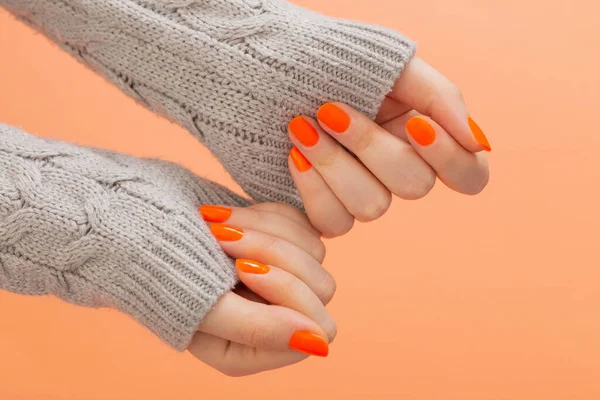 female hands with orange manicure   on  orange background