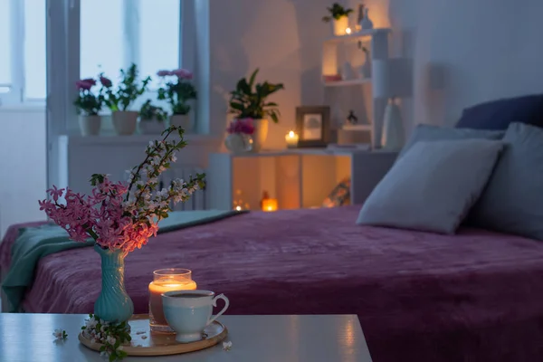 cozy bedroom in  evening with flowers and tea