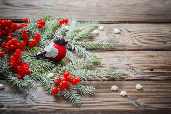 赤い果実とクリスマスの背景暗い木製のテーブルの上のガラスのブルフィンチとモミの枝 — ストック写真