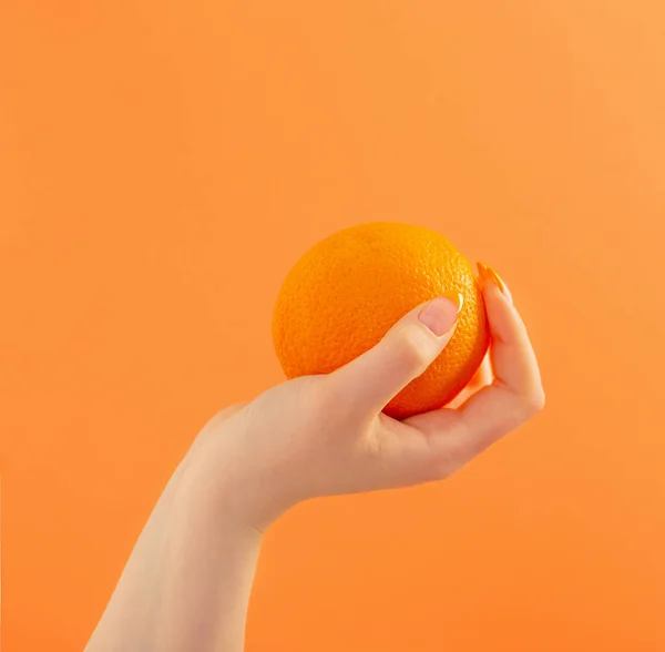 Vrouwelijke Hand Met Oranje Oranje Achtergrond — Stockfoto