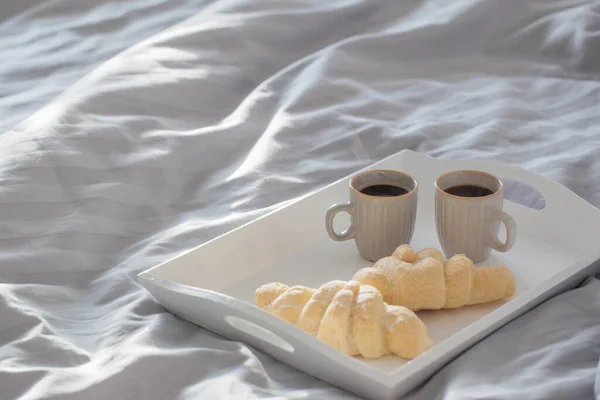 Zwei Croissants Und Zwei Tassen Kaffee Auf Dem Bett — Stockfoto