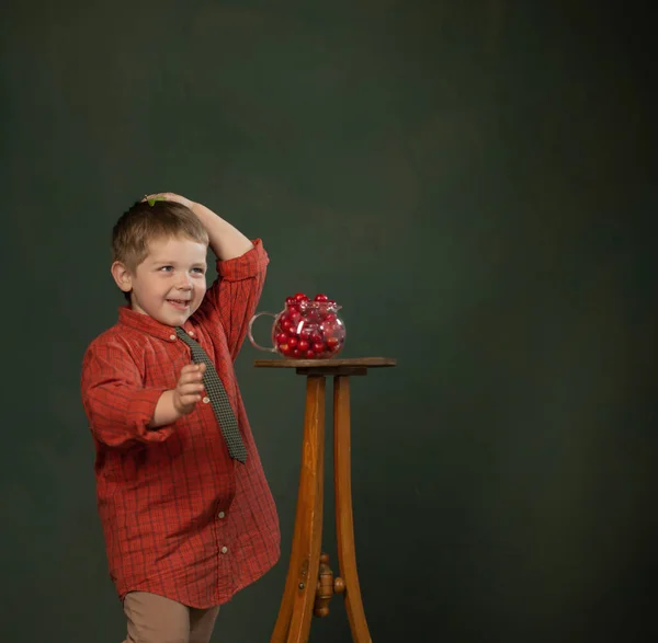 Liten Rolig Pojke Med Körsbär Bakgrunden Mörkgrön Vägg — Stockfoto