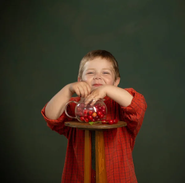 Μικρό Αστείο Αγόρι Κεράσια Στο Παρασκήνιο Σκούρο Πράσινο Τοίχο — Φωτογραφία Αρχείου