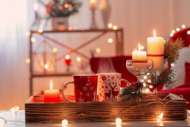 Evde beyaz ve kırmızı renklerde Noel süslemeleri olan bir fincan sıcak içecek.