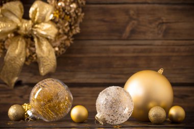 Koyu ahşap arka planda Noel altın topları ve çelenk