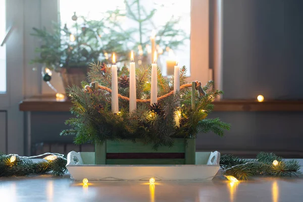 家庭の白いテーブルの上の木のバスケットにモミの枝と4つの燃えるろうそくの出現の装飾 — ストック写真