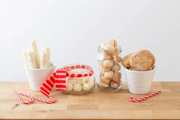 圣诞节糖果和饼干放在白色背景的木制架子上的罐子里 — 图库照片