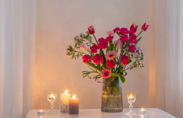 stock image pink flowers in glass modern vase with burning candles in white interior