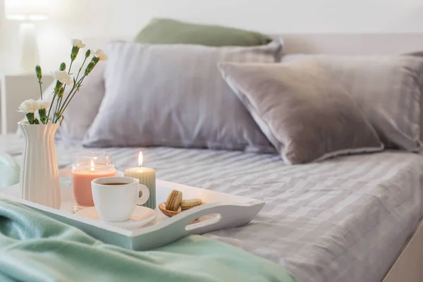 在床上的木制托盘上 放着鲜花和蜡烛的咖啡 — 图库照片